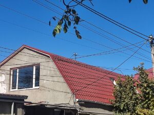 Мансардная крыша покрытая красной металлочерепицей. Октябрьское